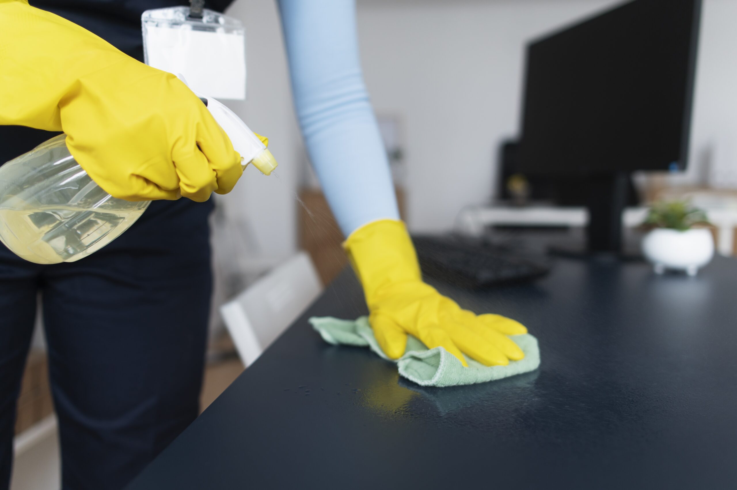 A person in yellow gloves cleaning the table.