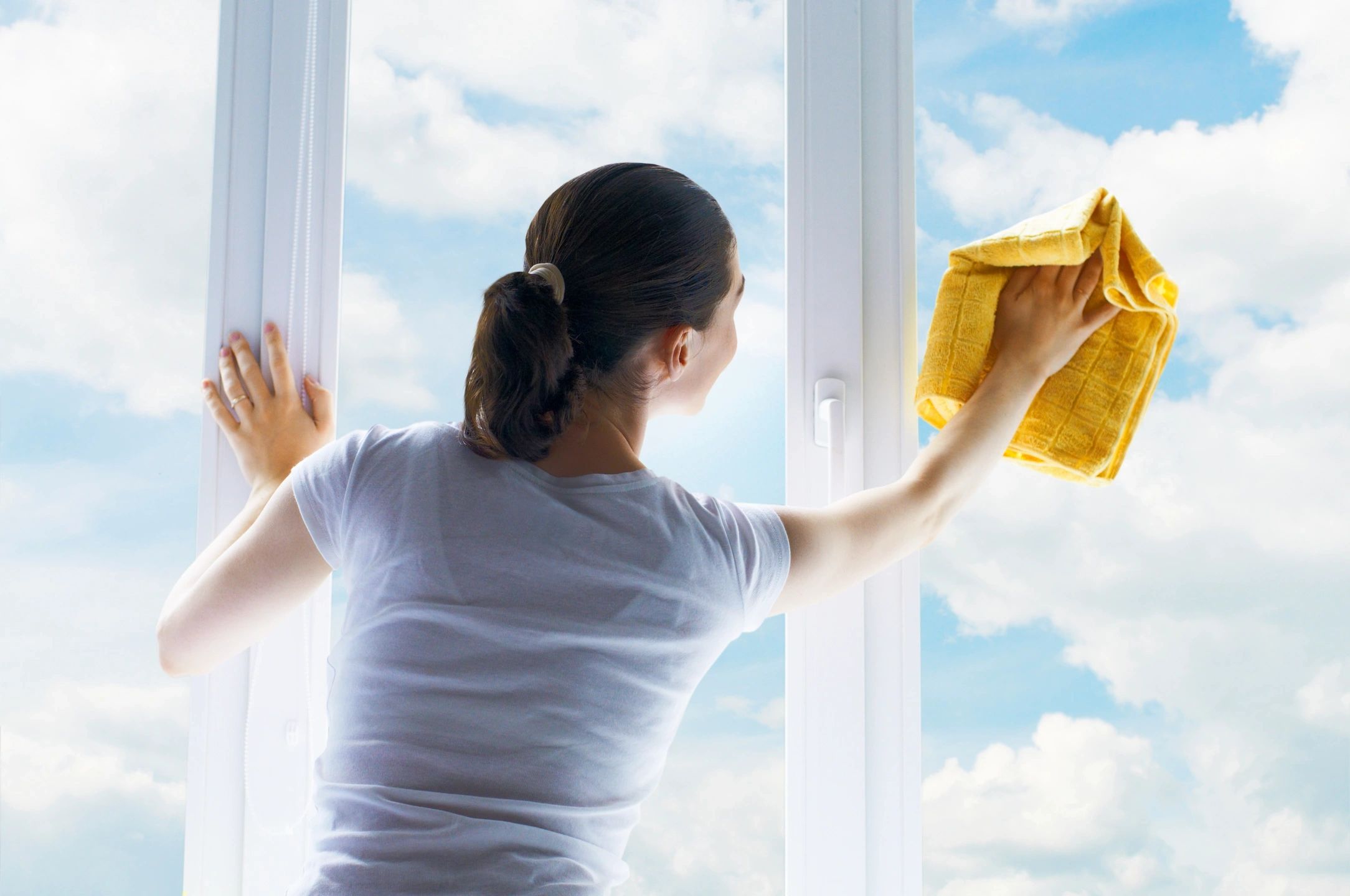 A woman cleaning windows with a cloth.